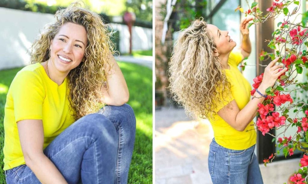 A joyful woman with curly hair in a yellow shirt outdoors.